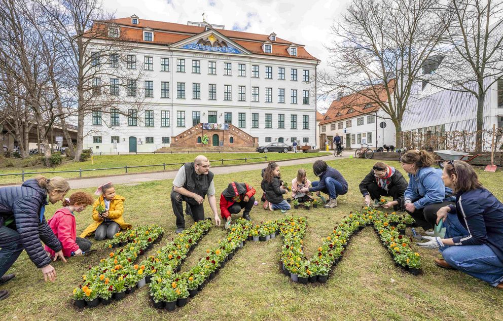 Kinder und Erwachsene pflanzen einen WIR-Schriftzug aus Hornveilchen