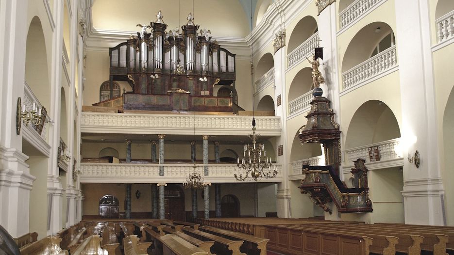 View into the interior of the Jesus Church in Cieszyn, featuring the large organ and the three galleries in the side aisle of the church, which open onto the main nave with semicircular arches.