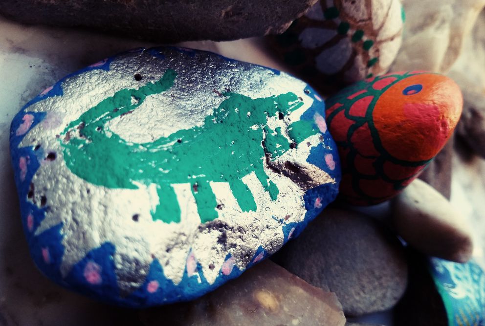 Ein Stein, der von Kindern mit einer bunten Krokodilfigur bemalt wurde, zeigt kreative Gestaltung und Fantasie