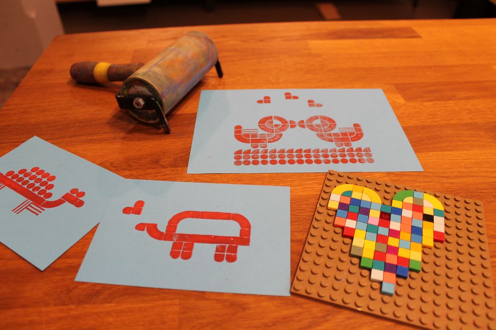 auf einem Tisch liegen eine Druckwalze, eine Herz-Vorlage und Blätter mit bedruckten Motiven