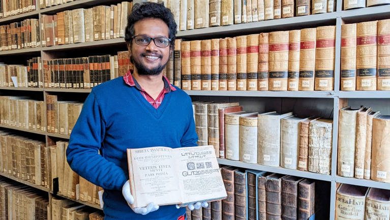 Earnest Philip Joshua, Bundesfreiwilliger im Programm weltwärts, zeigt in der Kulissenbibliothek der Franckeschen Stiftungen die Biblia Damulica, die vor 200 Jahren in Tharangambadi gedruckt wurde. 
