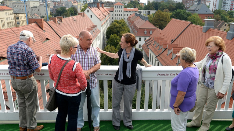Eine Herumführerin erklärt einer Besuchergruppe vom Altan aus die vielen Häuser der Schulstadt.