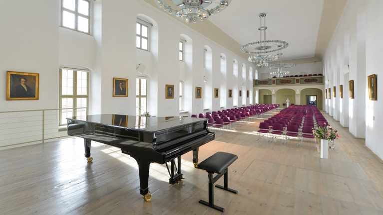 Ansicht des Festaals in den Franckeschen Stiftungen von der Bühne aus. Im Steinway Flügel spiegeln sich die Porträts der Stiftungsdirektoren an der Wand. S