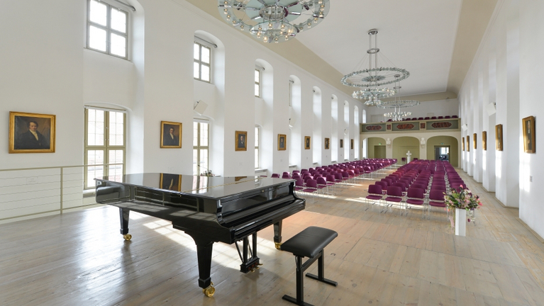 Ansicht des Festaals in den Franckeschen Stiftungen von der Bühne aus. Im Steinway Flügel spiegeln sich die Porträts der Stiftungsdirektoren an der Wand. S