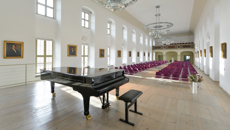 Ansicht des Festaals in den Franckeschen Stiftungen von der Bühne aus. Im Steinway Flügel spiegeln sich die Porträts der Stiftungsdirektoren an der Wand. S