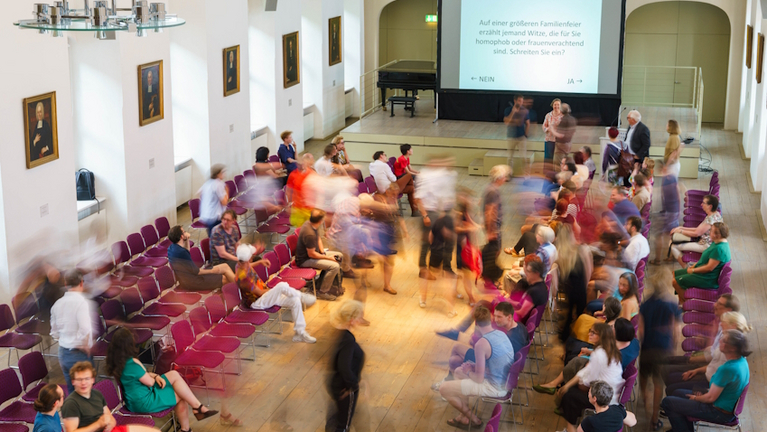 Der Freylinghausen-Saal mit Besucher:innen der Unterhausdebatte von oben