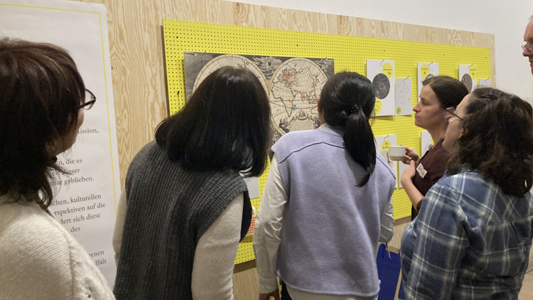 Besucherinnen diskutieren in der Ausstellung »Weltblicke« vor einer Weltkarte des 18. Jahrhunderts die Verortung ihrer heutigen Herkünftsländer.