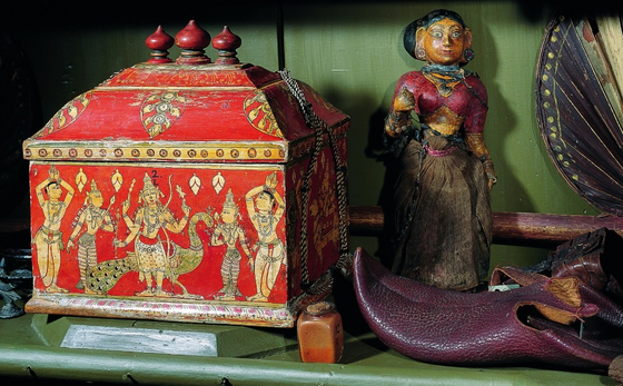 Details aus dem Indienschrank der Wunderkammer: ein reich verziertes Götzenkästlein neben einem nindischen Schuh und einer Puppe