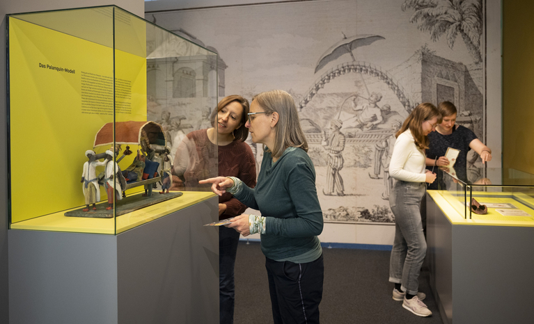 Vier Frauen schauen sich Objekte in den Schaukästen der Ausstellung an