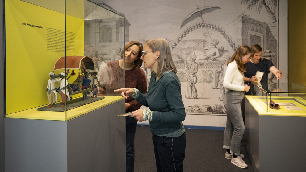 Vier Frauen schauen sich Objekte in den Schaukästen der Ausstellung an