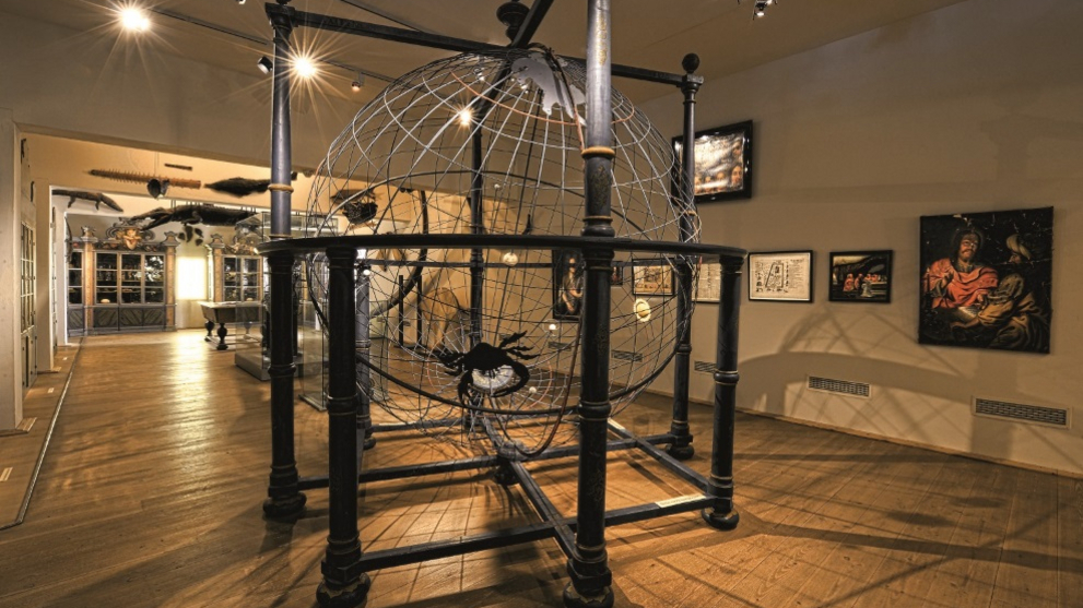 Blick in die Kunst- und Naturalienkammer mit dem raumgroßen Modell des Universums im Vordergrund.