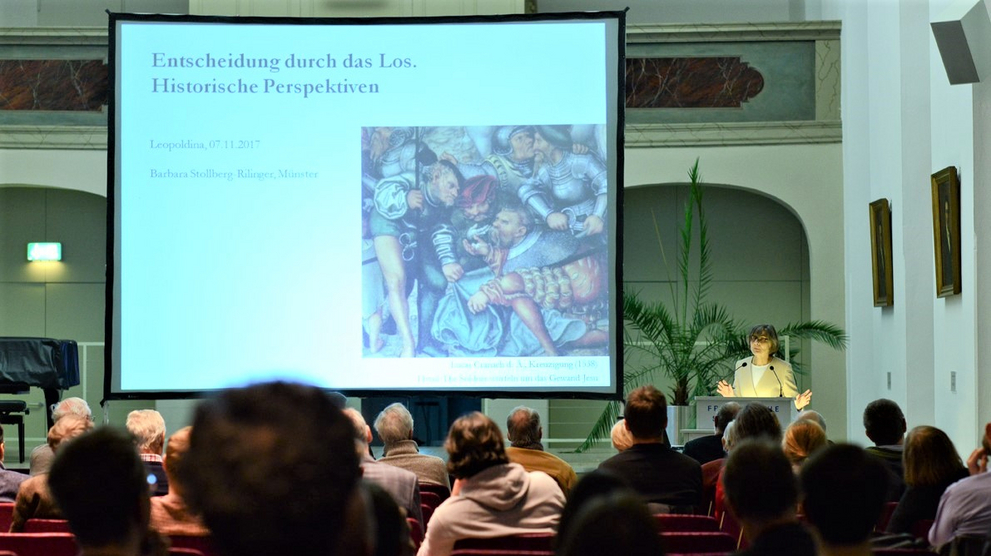 ZuhörerInnen des Vortrags von Frau Prof. Dr. Stollberg-Rillinger schauen im voll besetzten Freylinghausen-Saal auf eine anschaulich gestaltete Power-Point-Präsentation.
