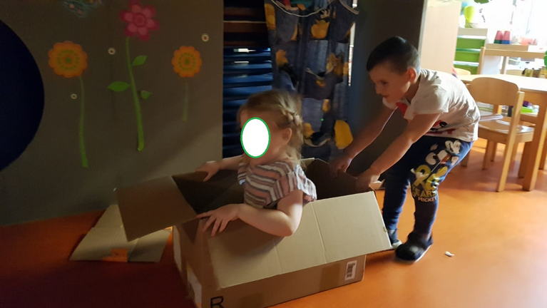 ein Kind sitzt im Karton, der Junge zieht den Karton 