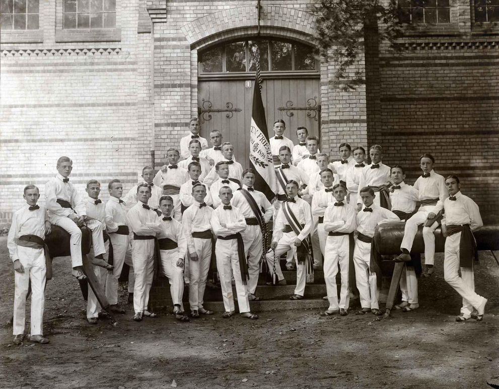 Group picture of the Friesen school gymnastics club with club flag in front of the sports hall