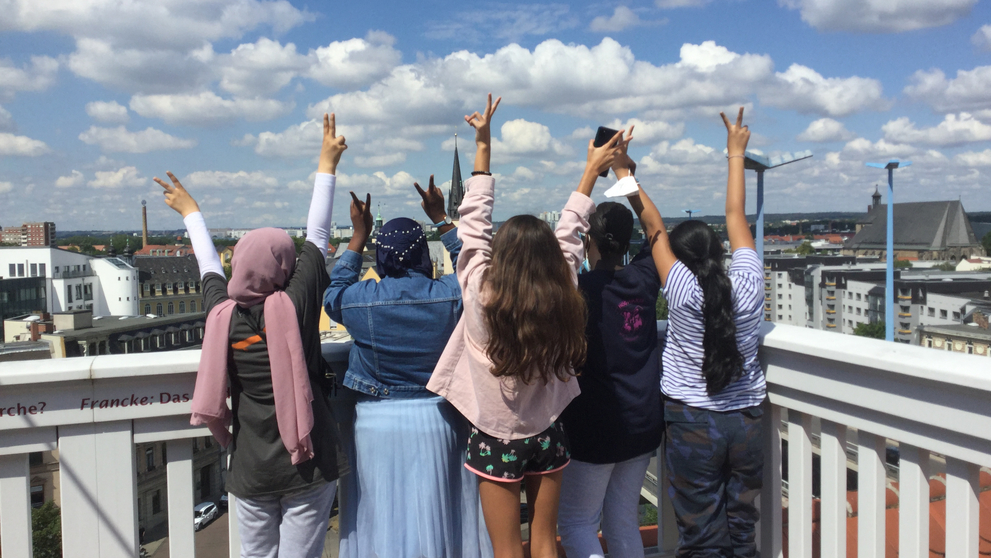 Kinder stehen auf dem Altan und zeigen zum Himmel