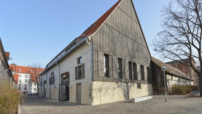 View of the Great Barn from the south. The gable clad in dark wood makes the large, white building shine.