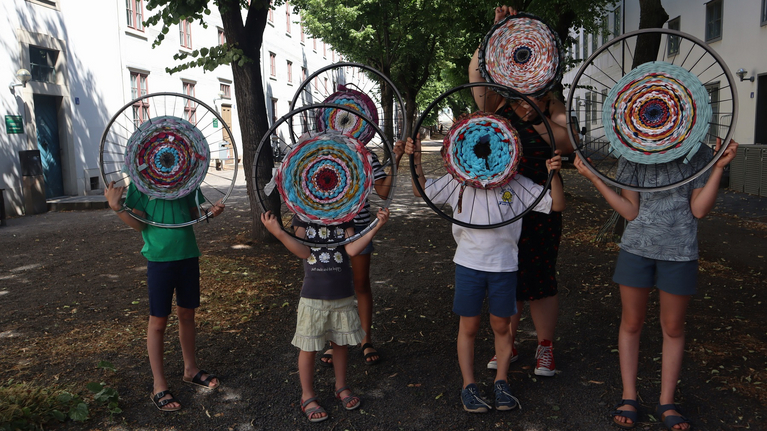 Kinder halten runde Webrahmen in die Luft