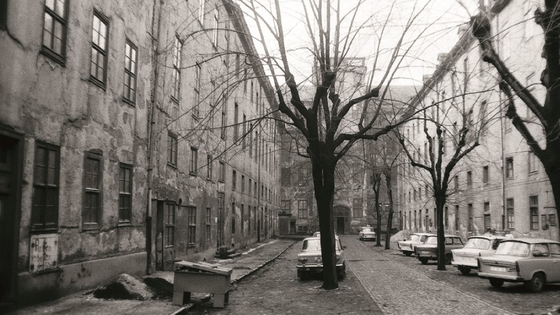 View into the Lindenhof with the buildings in need of renovation to the right and left hand and countless parked satellites.