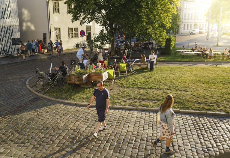 Besucher:innen auf der Wiese vor dem Waisenhaus im Abendlicht